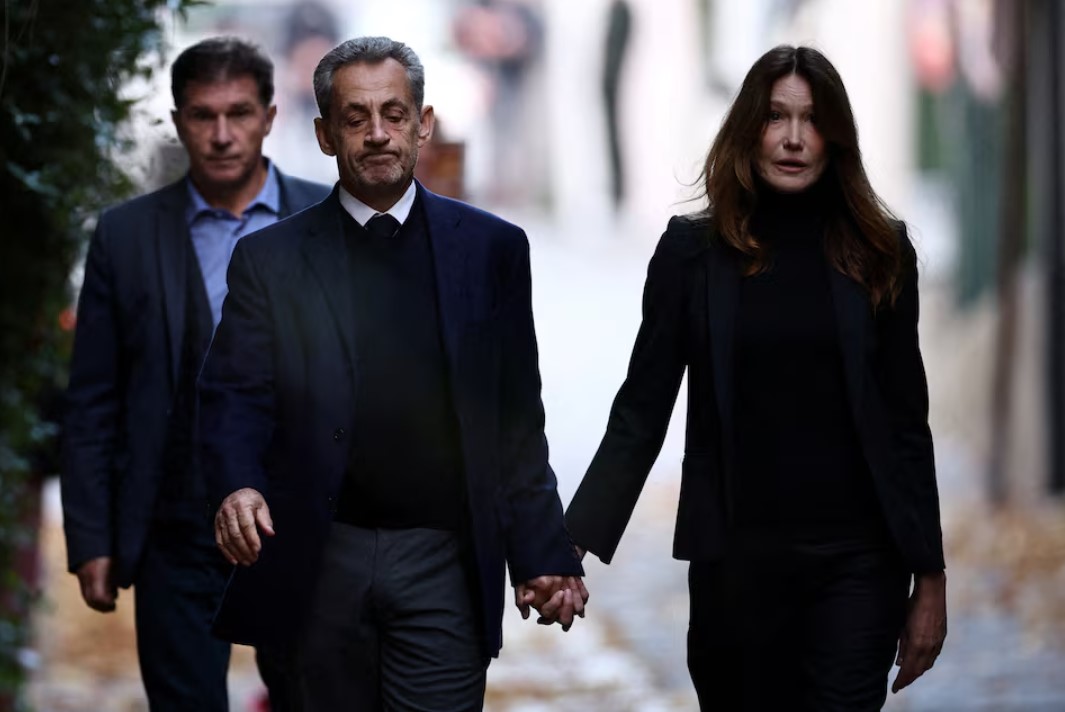 Former French President Nicolas Sarkozy leaves his house with his wife Carla Bruni-Sarkozy on the day of his incarceration at the Sante prison to begin his five-year prison sentence for criminal conspiracy over attempts to raise campaign funds from Libya, in Paris, France, October 21, 2025.