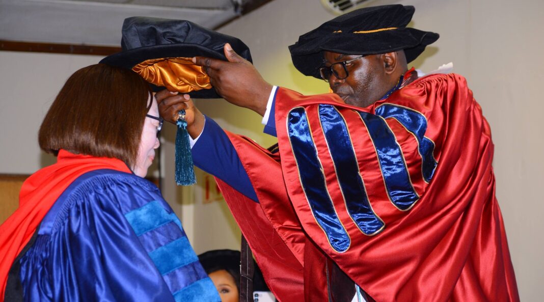 Professor John Mumba, acting Vice-Chancellor of Gideon Robert University, places the doctoral bonnet on Senator Dr Stukie Motsa during the hooding ceremony.